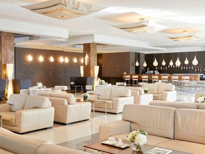 Helles, modernes Café mit bequemen hellen Sofas, Tischen, warmen Holz- und Beleuchtungselementen.