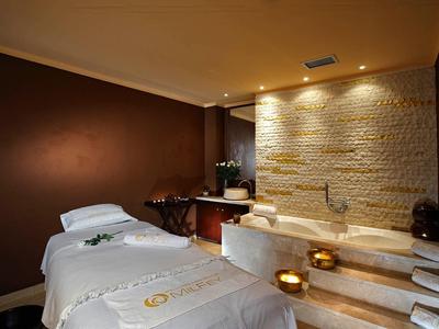 Gemütlicher Wellnessraum mit Massagebett, beleuchtetem Marmorbad und ruhiger, warmer Atmosphäre.