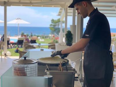 Mitarbeiter bereitet Speisen in einem offenen Hotelrestaurant mit Meerblick zu.