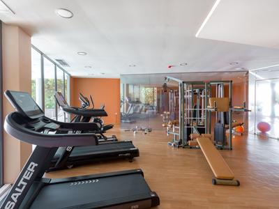 Moderner Fitnessraum mit Laufbändern und Kraftgeräten in hellem, geräumigem Raum