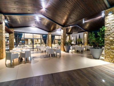 Elegantní venkovní restaurace s dřevěným stropem a bílými prostřenými stoly v hotelovém prostředí.