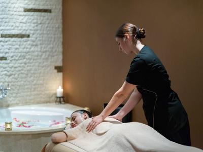 Masérka masíruje muže ležícího na masážním stole v relaxačním prostoru.