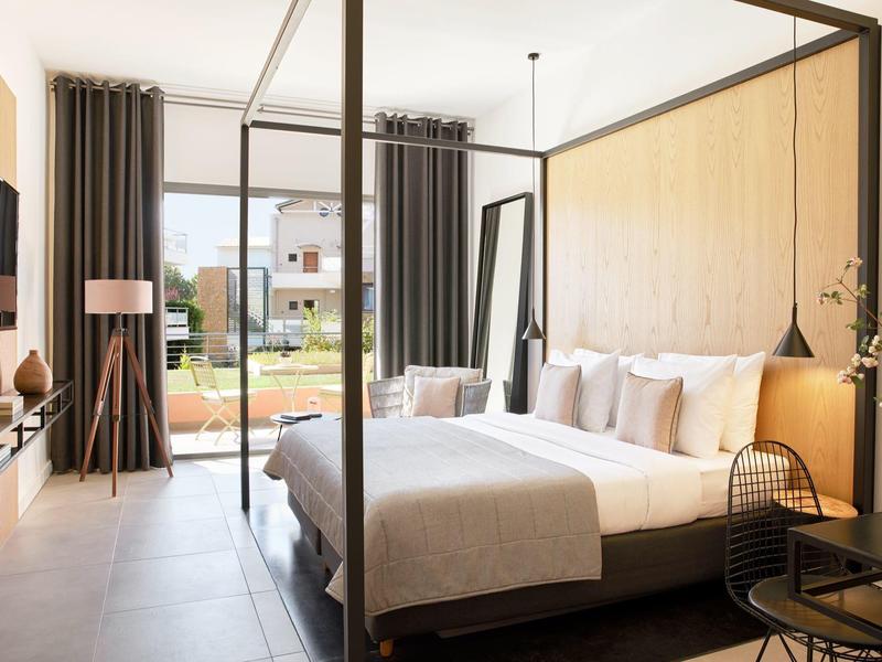 Moderní ložnice s postelí s nebesy, velkými okny a výhledem na zahradu