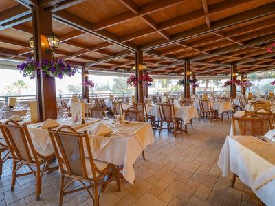 Prostorná restaurace s prostřenými stoly, dřevěným stropem a světlou dlažbou.