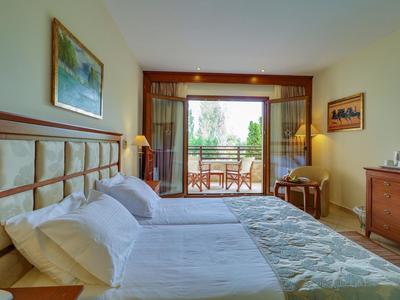 Světý hotelový pokoj s manželskou postelí, balkónem a výhledem do zeleně.