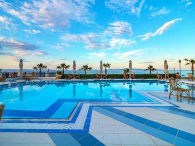 Großer Hotelpool mit klar blauem Wasser und Palmen bei Sonnenuntergang