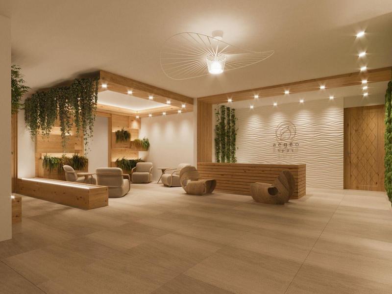 Moderní hotelová hala s dřevěnou výzdobou, rostlinami a pohodlnými sedačkami.