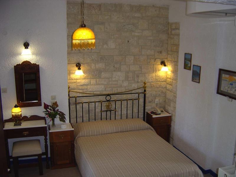 Przytulna sypialnia z ceglaną ścianą, metalową ramą łóżka, ciepłym oświetleniem i stolikami nocnymi.