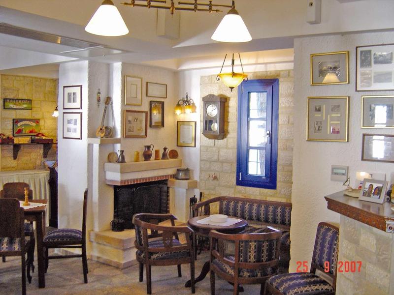 Przytulny kącik z drewnianymi krzesłami, małym stołem, kominkiem i niebieskim oknem w ciepło urządzonym pokoju.