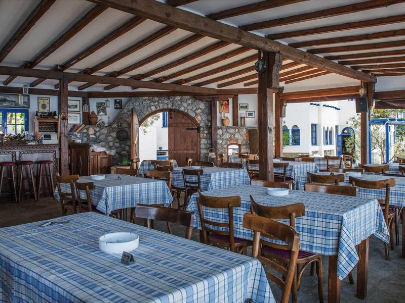 Przytulna restauracja na zewnątrz z kraciastymi obrusami, drewnianymi belkami i barem.