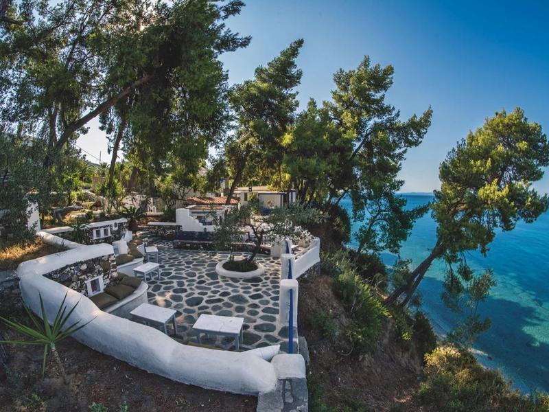 Kamienny taras z miejscami do siedzenia nad błękitnym oceanem i drzewami na klifie.