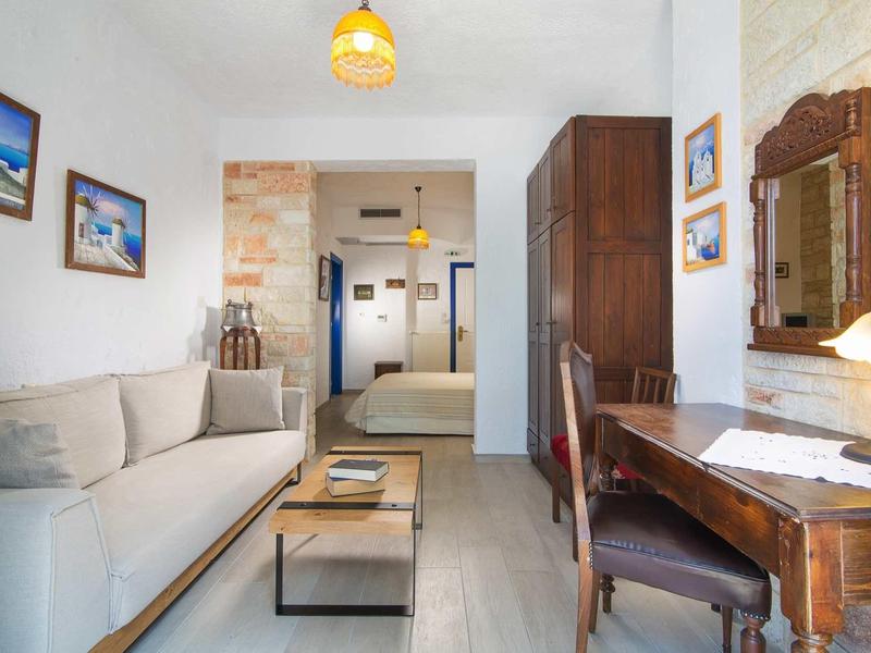 Jasny pokój hotelowy z sofą, drewnianym biurkiem i łóżkiem w tle.