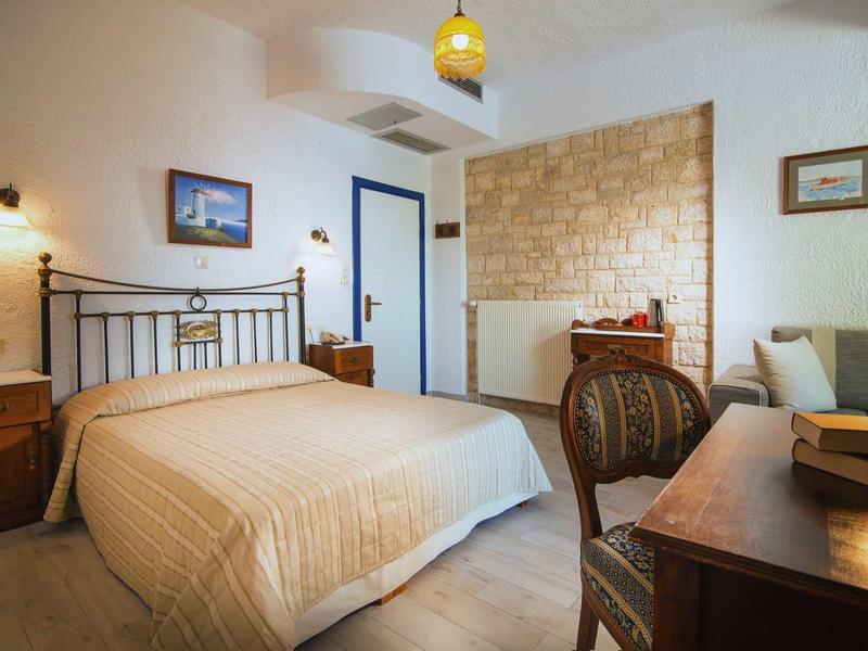 Przytulny pokój hotelowy z podwójnym łóżkiem, drewnianymi meblami i ciepłym oświetleniem.