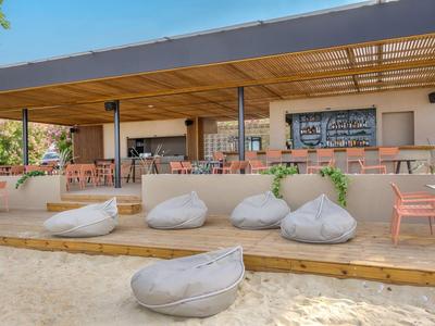Zona de playa abierta con pufs y una terraza de hotel amueblada.