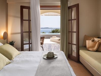 Dormitorio con balcón abierto y vistas al mar, interior luminoso con asientos cómodos.