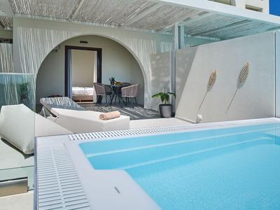 Área exterior moderna con piscina, tumbonas y zona de estar en un hotel.
