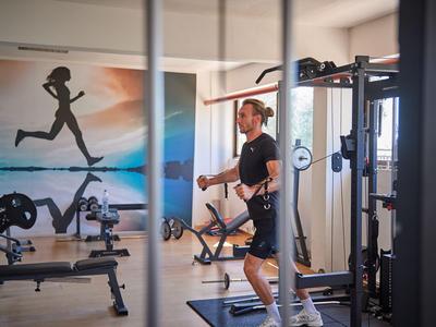 Joven entrena con máquina de poleas en gimnasio de hotel bien equipado.