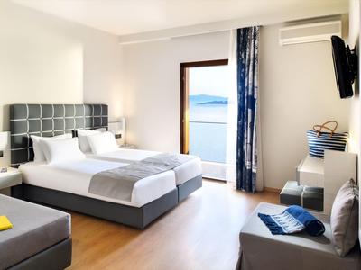 Habitación de hotel moderna con cama doble, balcón con vista al mar y zona de estar.