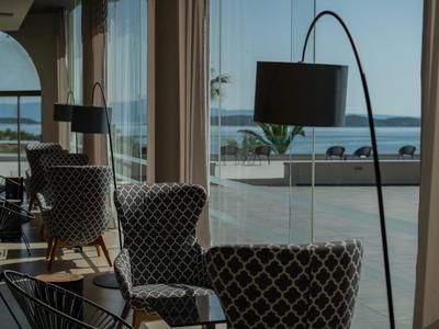 Salón moderno con sillones tapizados y gran ventana con vista al mar de fondo.