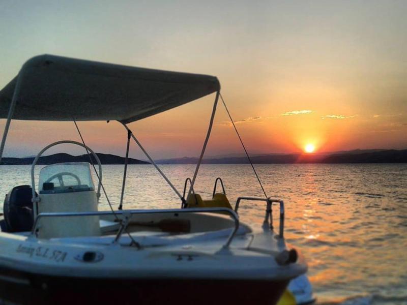 Loď přistavěná u břehu při západu slunce nad klidnou vodou