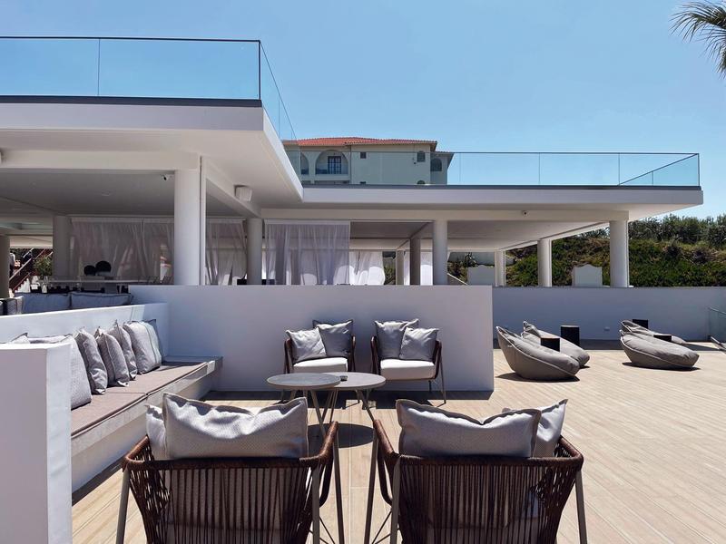 Moderní venkovní prostor s posezením a lehátky pod jasnou oblohou.