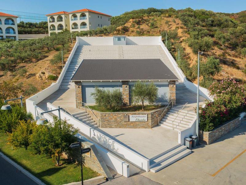 Moderní venkovní bazén s terasou na opalování v kopcovém hotelovém komplexu