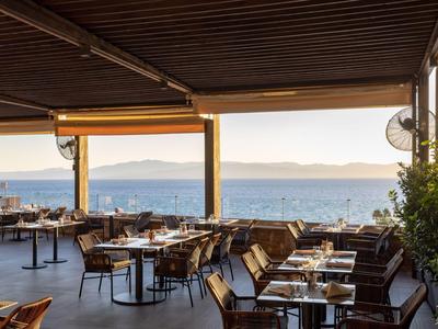 Terraza cubierta de restaurante con vista al mar y mesas preparadas.