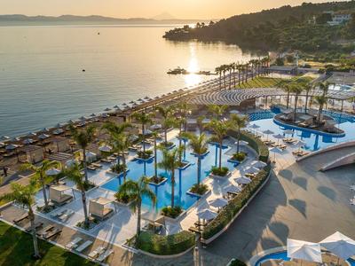 Zona de piscina de lujo con palmeras junto al mar al atardecer