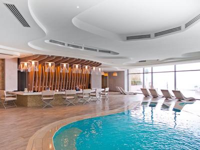 Vnitřní bazén s lehátky a velkými okny pro přirozené světlo.