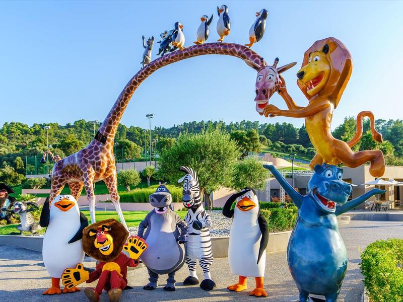 Postavy z filmu Madagaskar v barevných velkých sochách na slunečném venkovním parku.