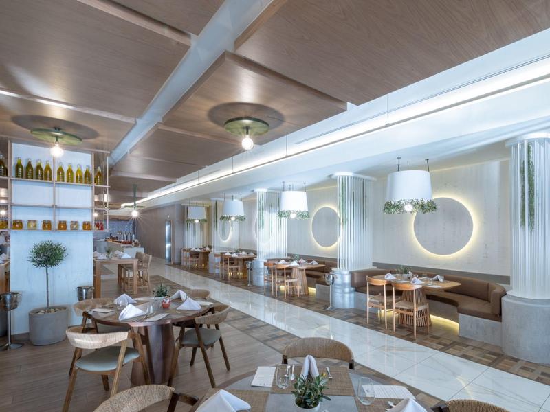 Světelná moderní restaurace s kruhovými zrcadly, útulnými sezeními a elegantním osvětlením.