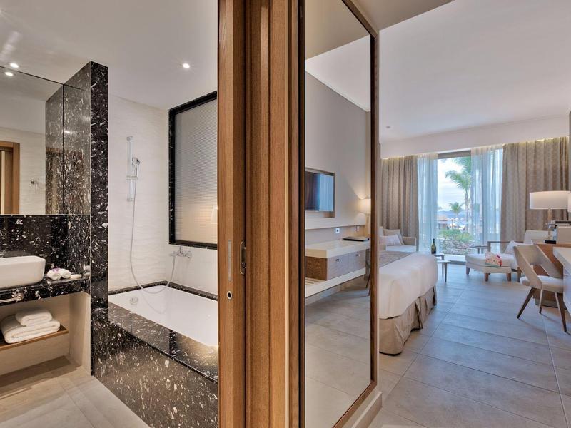 Moderní hotelový pokoj s koupelnou s mramorem a ložnicí s balkonem.