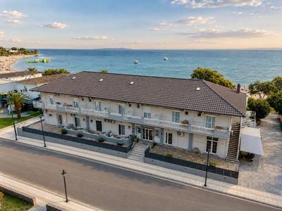 Moderner zweistöckiger Hotelbau nahe Küste mit Meerblick und klar blauem Himmel.