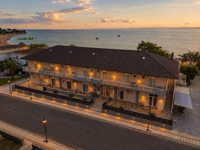 Zweistöckiges Hotel an der Küste mit beleuchteten Räumen bei Sonnenuntergang.