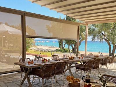 Terrasse eines Hotels mit Tisch und Stühlen, Blick auf Meer und Bäume im Hintergrund.