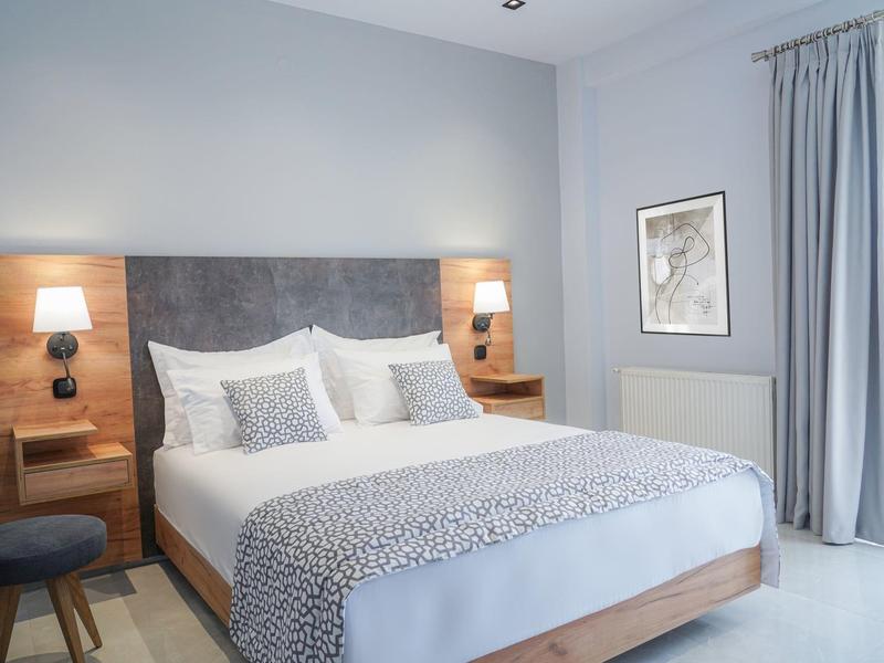 Nowoczesna sypialnia z podwójnym łóżkiem, szarym zagłówkiem i lampkami na stolikach nocnych