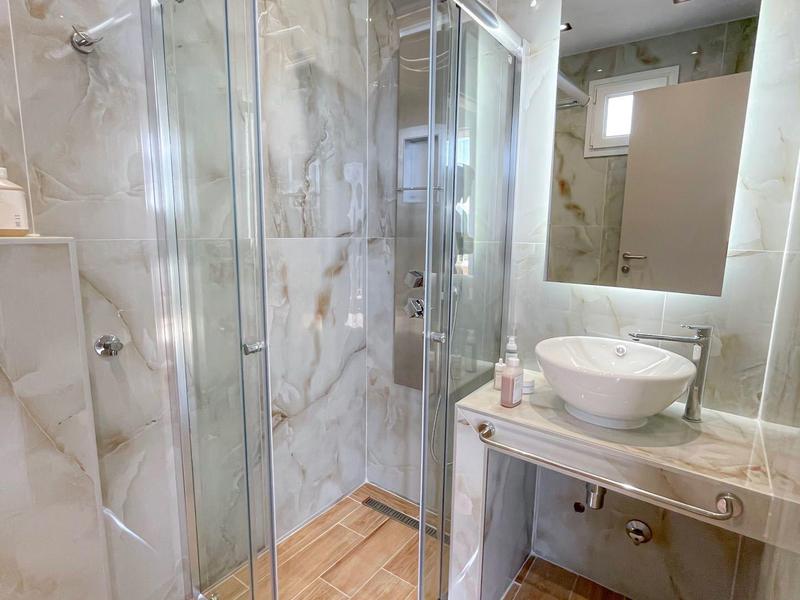 Nowoczesna łazienka z przeszkloną kabiną prysznicową, umywalką na konsoli i kafelkowaną podłogą.