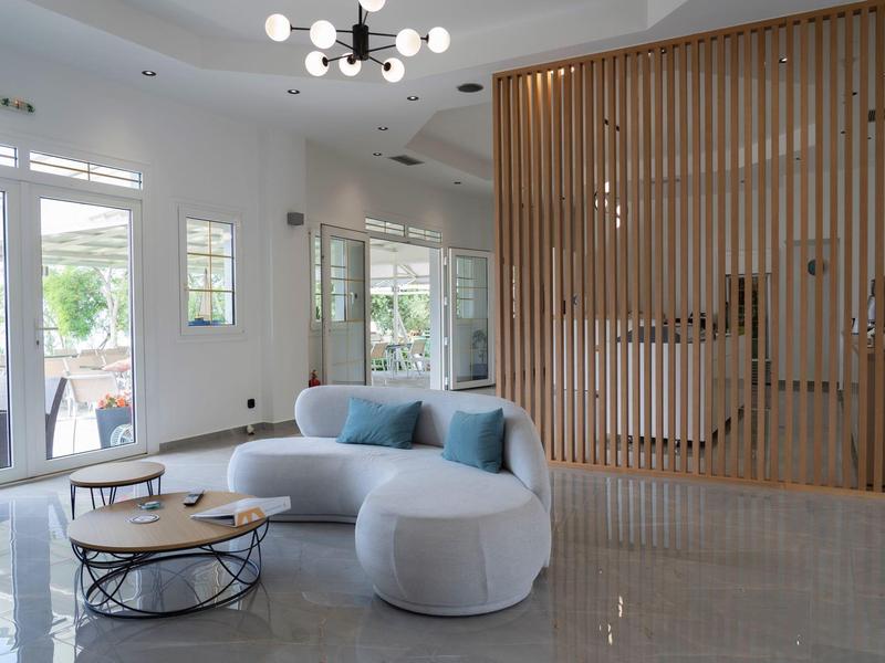 Nowoczesny salon z białą sofą, niebieskimi poduszkami i drewnianą ścianką w jasnym pomieszczeniu.