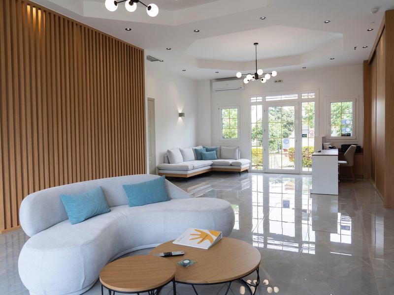 Nowoczesne lobby hotelowe z białymi sofami, drewnianymi ścianami i jasnymi płytkami.