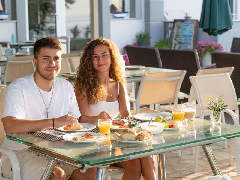 Para ciesząca się śniadaniem z sokiem pomarańczowym przy szklanym stole na tarasie.