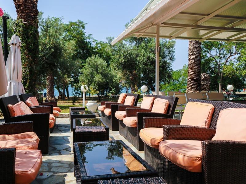 Przytulny salon na zewnątrz z miejscami do siedzenia i widokiem na zielone drzewa i morze