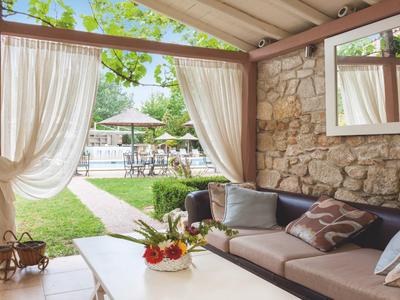 Przytulny zadaszony taras z miejscem do siedzenia z widokiem na basen w ogrodzie.