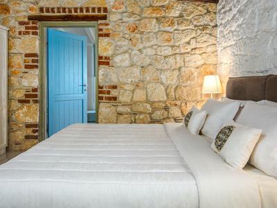 Cozy bedroom with exposed stone wall and blue door, bed with white and patterned pillows.
