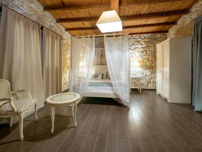 Cozy hotel room with wooden beam ceiling, elegant curtains, and antique furniture.