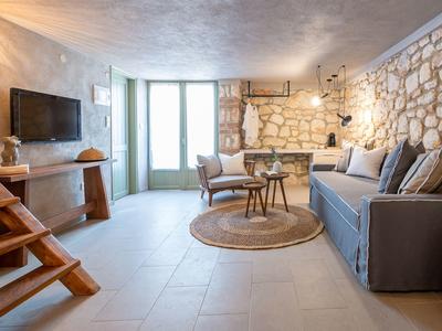 Living room with stone wall, gray sofa, round rug, and large window in modern design.