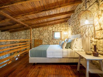 Cozy bedroom with wooden beam ceiling and stone walls in rustic style.