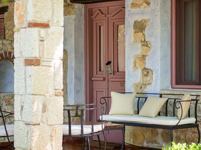 Bench on a terrace with stone wall and door in the background.