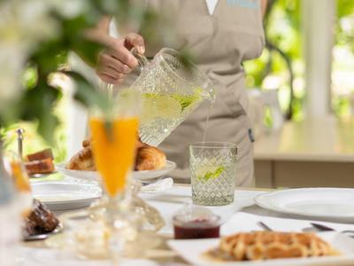 Person pouring a drink into a glass on a set table outdoors.