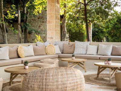Cozy outdoor lounge with cushioned seating, wooden tables, and natural plants