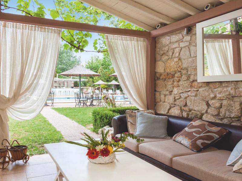 Cozy covered patio seating area with view of pool and garden